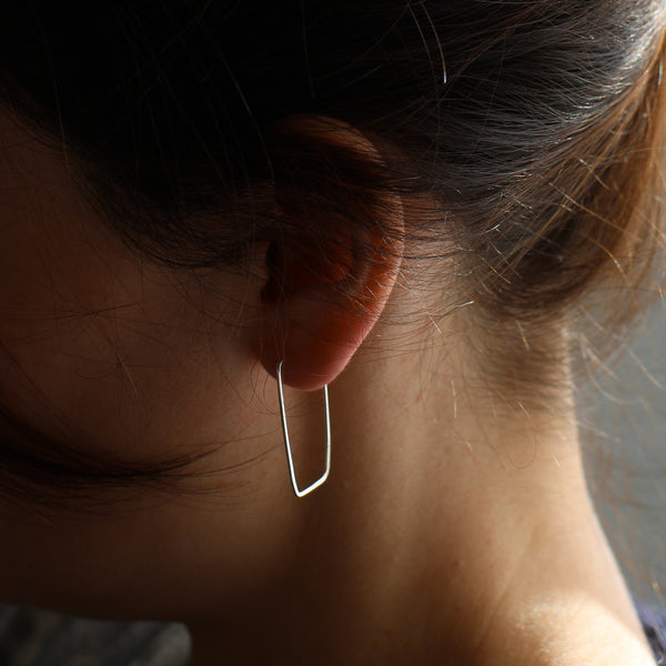 Thin silver hoop earrings on model